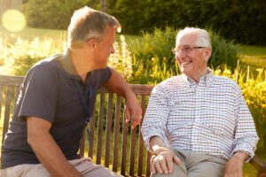 An older adult and family member review a daily care checklist at a kitchen table.